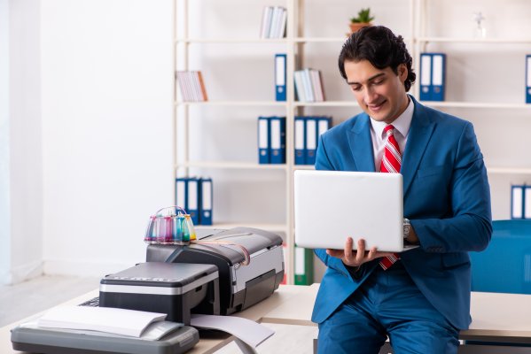 best free internet online fax service man in blue suit with laptop in hands near fax machine in office folders in the background gotfreefax